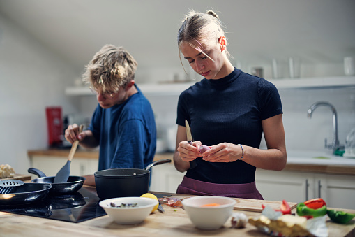 Teenagers preparing lunch. The girl is peeling onion and the boy is mixing the frying vegetables.
Shot with Canon R5