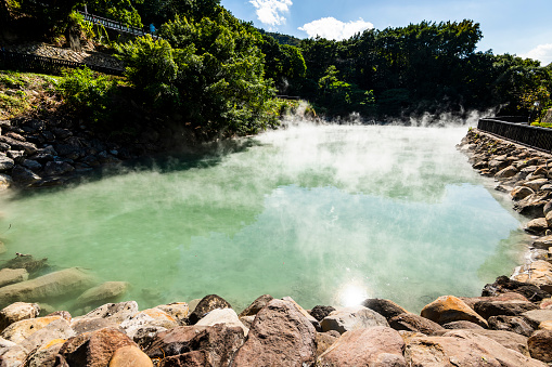 Colorful orange - green Champagne Pool in the Waiotapu Thermal Wonderland. The pool is a 65 m wide spring, containing multiple minerals that are presently depositing in the surrounding sinter ledge. Waiotapu, North Island, New Zealand.