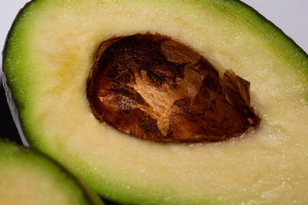 アボカドと呼ばれる非常においしい果物の写真は、非常に興味深い茶色の種子が内部にあります。 - avocado portion brown apple core ストックフォトと画像