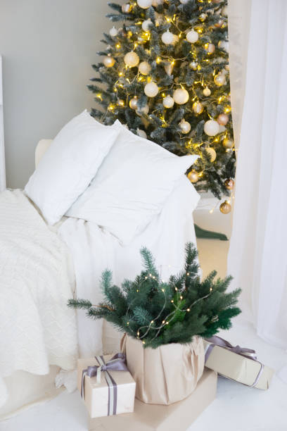 istock Bright interior with a false fireplace decorated for Christmas. Christmas trees with garlands, balloons and lights. 1879165337