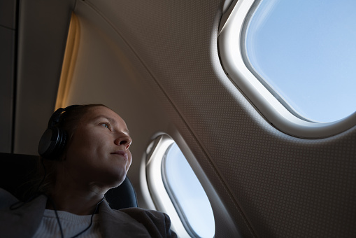 Woman seating in the airplane looking out of the window