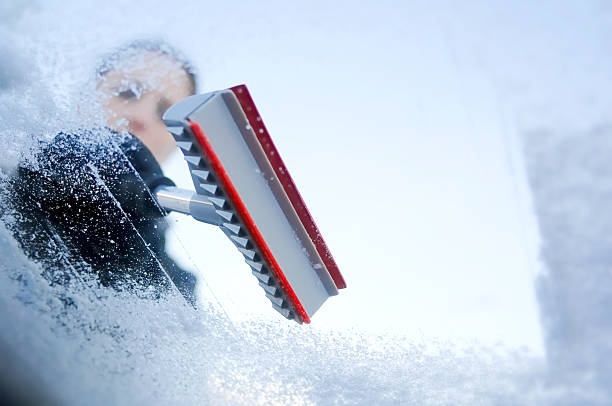 Person scraping ice from a windshield stock photo