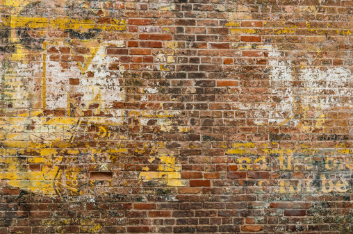 Faint remnant of an old advertisement on the brick wall of an old building.