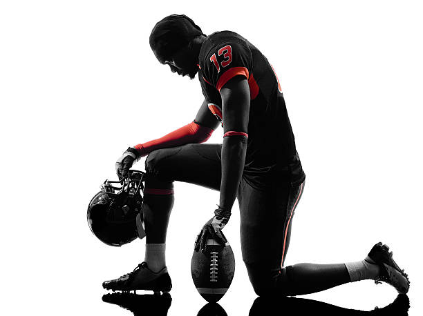 american-football-spieler kniend silhouette - kneeling stock-fotos und bilder