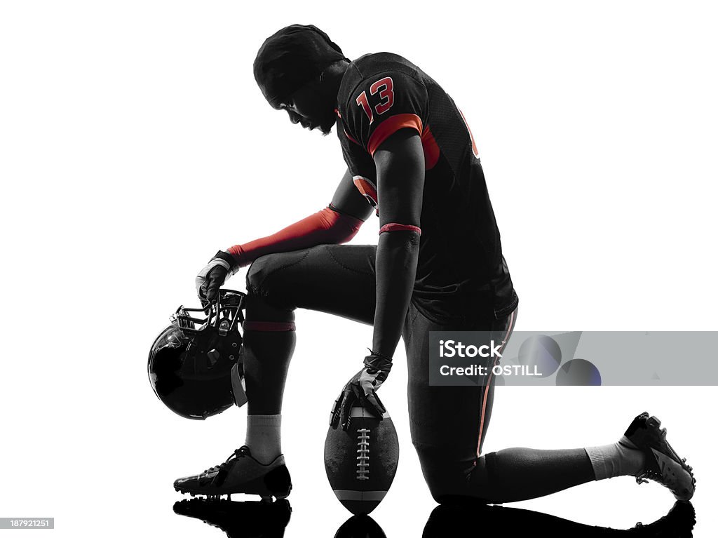 american football player kneeling silhouette one american football player kneeling in silhouette shadow on white background Kneeling Stock Photo