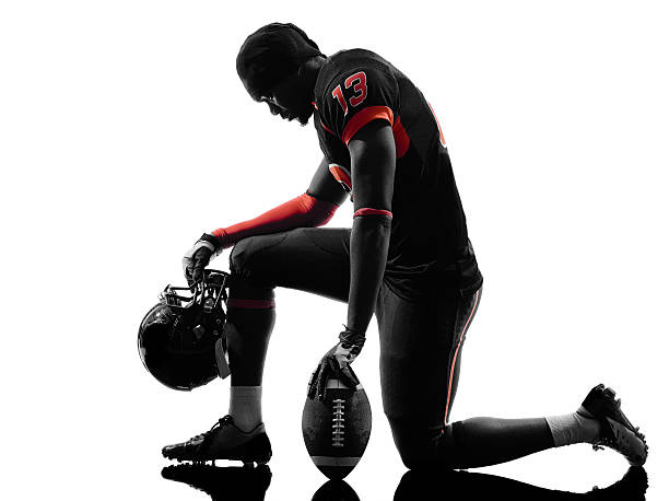 american football player kneeling silhouette one american football player kneeling in silhouette shadow on white background kneeling stock pictures, royalty-free photos & images