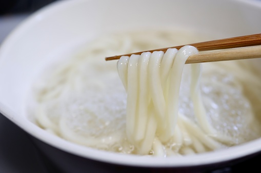 Boiling Sanuki udon noodles in a hand-pot. Sanuki udon is a traditional dish of Kagawa Prefecture in Japan.