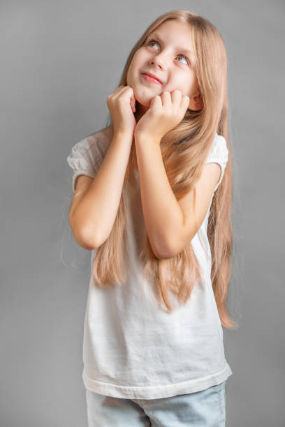 Portrait of positive cheerful girl cutely smiling Portrait of positive cheerful girl cutely smiling, girl with long blonde hair in white t-shirt cutely stock pictures, royalty-free photos & images