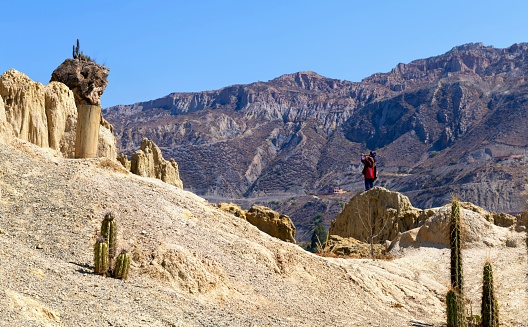 La Paz, Bolivia, October 15, 2023: An indigenous musician plays the flute on a rock formation in the Valle de la Luna outside the city of La Paz.