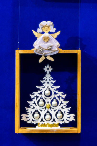 Decorative Christmas tree in a wooden frame. An angel sits on the frame. Christmas tree with a trident - a symbol of Ukraine