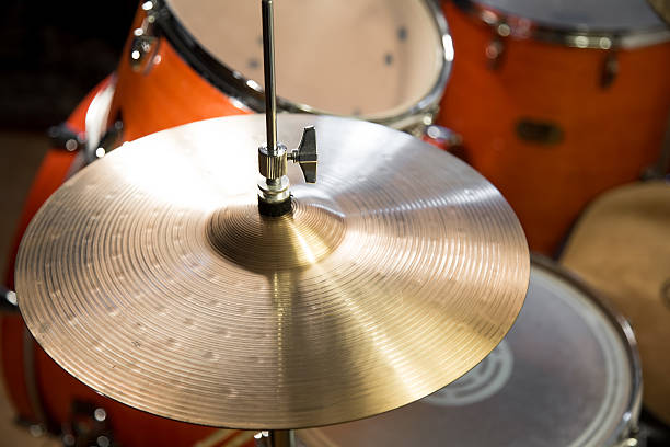 shiny hi-hat cymbals on stand with wooden orange drum-kit stock photo