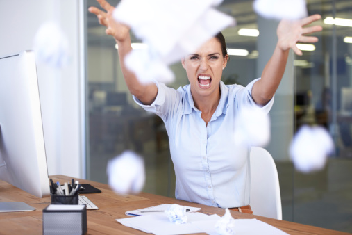 Portrait of an angry businesswoman throwing papers towards the camera