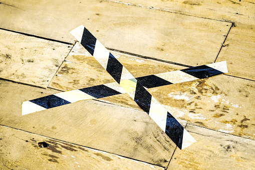 Cordon Crime Line Tape for further investigations. Crossed caution and danger line. Black and yellow warning, police tapes, attention, sign line. Set of warning tapes stick on wooden floor backgrounds