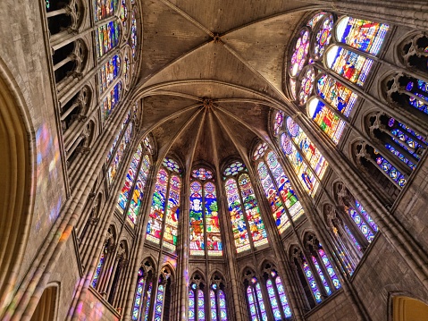The Basilica of Saint-Denisis a large former medieval abbey church and present cathedral in the commune of Saint-Denis, a northern suburb of Paris. The church was completed in 1144 and widely considered the first structure to employ all of the elements of Gothic architecture. The image shows the ceiling and stained glass windows of that magnificant cathedral.