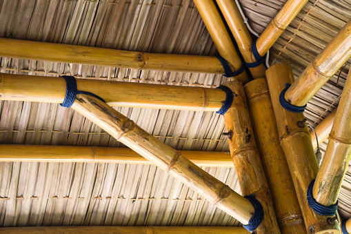 Wooden Roof of Traditional House in Indonesia. Bamboo pillar column with woven straw roofing and ceilings. Gazebo structure design for tropical beach resort.