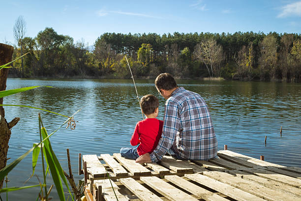 Father teaching his son how to fish in beautiful mountain lake.