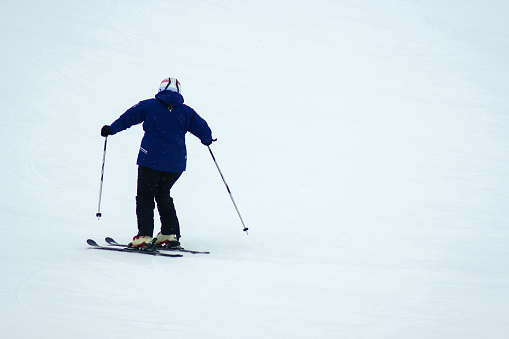 Person skiing down a slope, winter entertainment, winter time. Copy space. Selective focus
