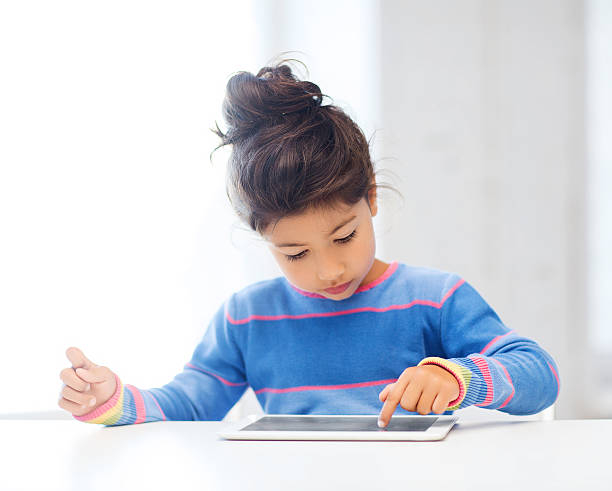 istock Girl with her hair in a bun playing on a tablet pc 187938371