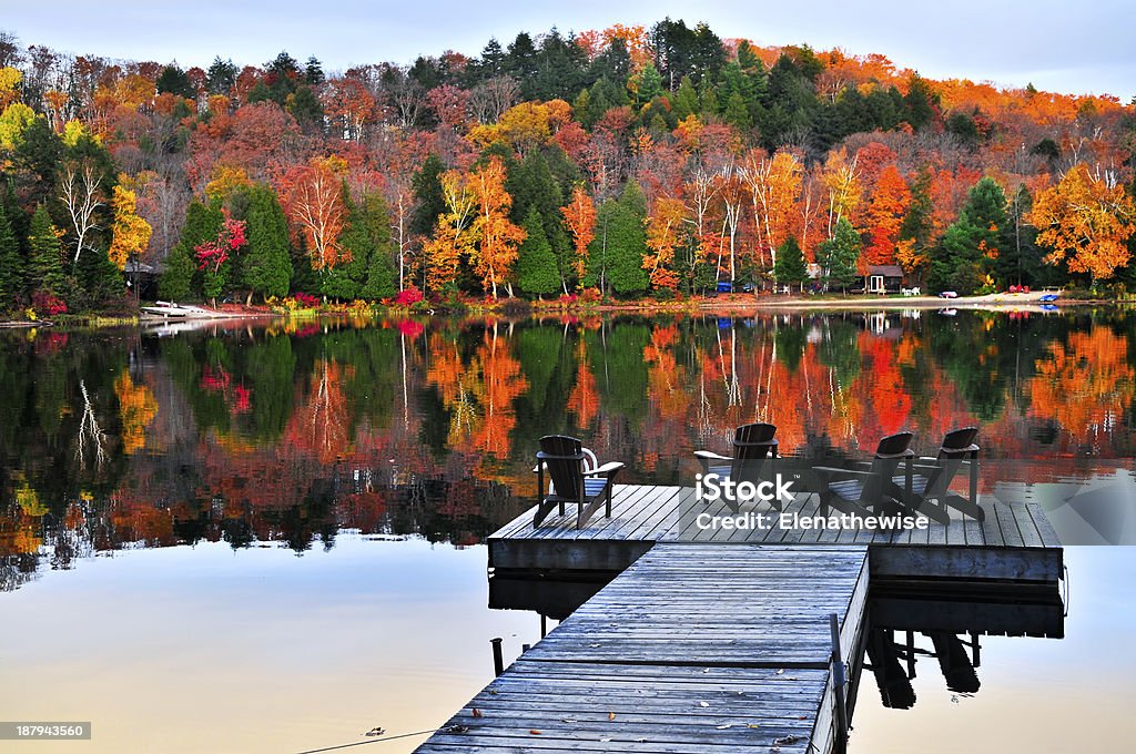 Wooden dock on autumn lake Wooden dock with chairs on calm fall lake Autumn Stock Photo