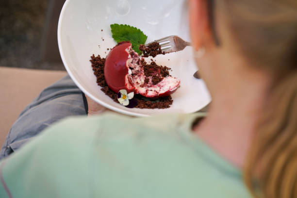 vue de dos, par-dessus l’épaule d’une femme mangeant un dessert en forme de pomme rouge. - cheesecake syrup cottage cheese cream photos et images de collection