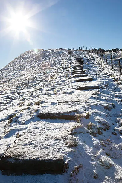 Paving slab steps on the side of a snowy Whernside - one of the mountains known as the Yorkshire Three Peaks in the Yorkshire Dales National Park, England.