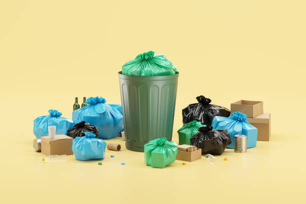 istock Full trash bin with plastic bags and cardboard boxes, yellow background 1879501769