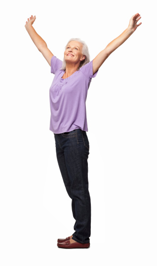 Full length of senior woman in casual wear looking up while standing with arms raised. Vertical shot. Isolated on white.