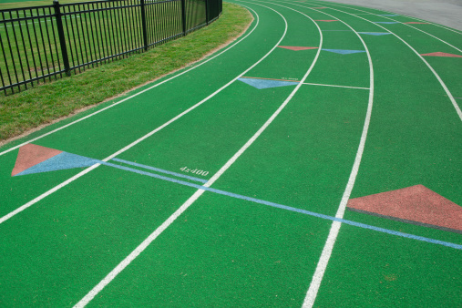 this picture is of Track Lanes at a Track and Field Running Event. lane one and lane two are in the picture. and the picture is a close up of lane one at a track and field event. the picture was taken at a sporting event. the lighting is natural sunlight. and the picture was taken during the day. 