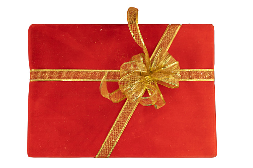 A red gift box tied with a golden ribbon on white background, representing the tradition of gift-giving during the festive Christmas season.