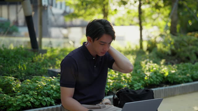 Man Expresses Stress on Laptop at a Serene Park Bench.