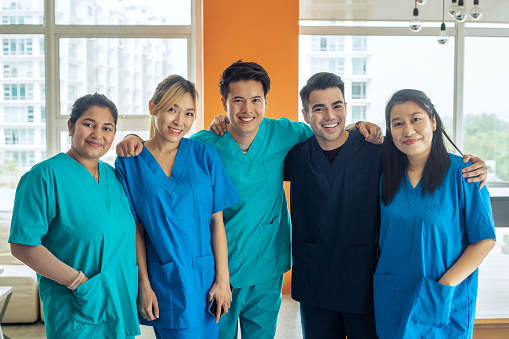 portrait of multi racial Medical professionals in scrubs standing together in positive emotions looking at camera