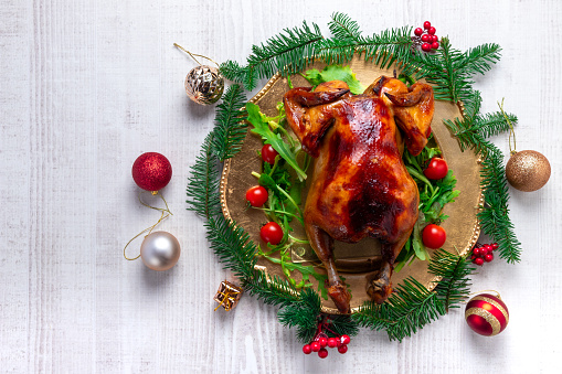 Roasted whole chicken with Christmas decoration. White wooden background. Top view.