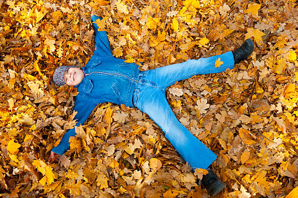 istock boy lying on yellow leaves in autumn park 187956059