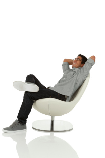 Young adult relaxing on chair with hands behind head looking up isolated on white