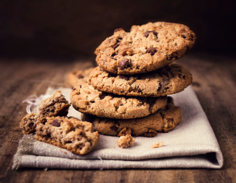 Chocolate chip cookies on linen napkin on wooden table. Stacked chocolate chip cookies close up.