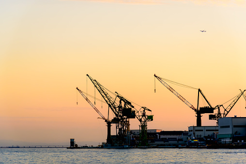 Cranes at the quayside of an empty commercial dock, with a ferry in the distance.  Belfast, Northern Ireland.