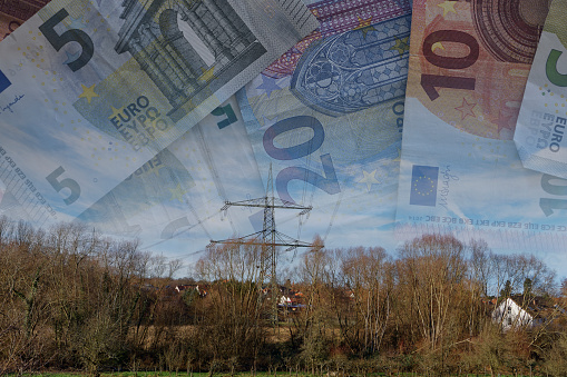 High voltage pylons, close to a residential area. Banknotes as a symbol of exploding energy prices.