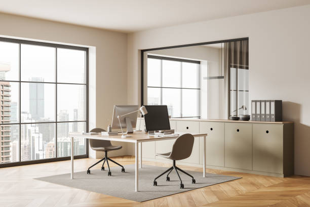 istock Beige coworking interior with pc monitors and drawer with folders and window 1879636151