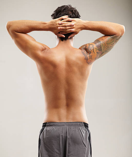 He takes stretching seriously Rearview of a shirtless man stretching his neck before a workout body adornment rear view young men men stock pictures, royalty-free photos & images