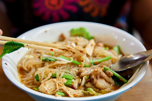 Cropped hand of woman having rice stick noodles in a bowl