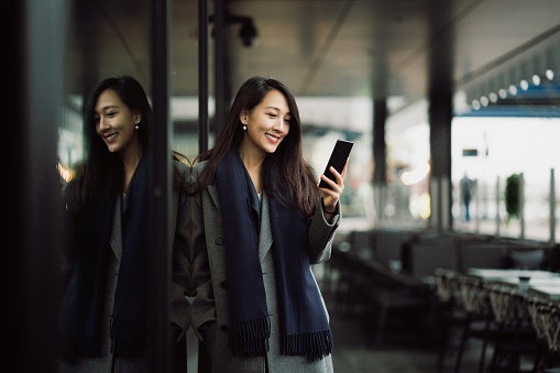 Asian businesswoman using her phone in a financial area.
