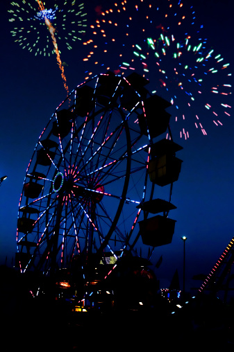 Fireworks and a ferris wheel or big wheel at a fair or carnival
