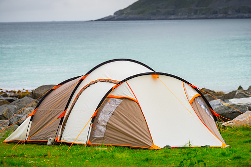 Tent on seashore in summer, cloudy hazy weather. Camping on ocean shore. Skagsanden Beach Flakstadoy Lofoten Norway. Holidays travel and adventure.