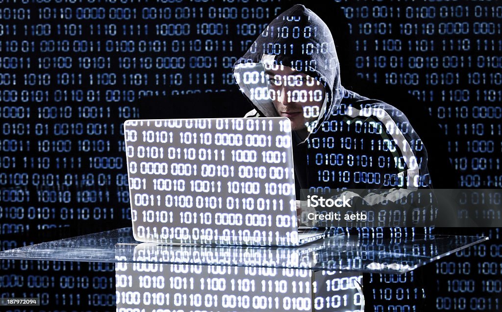 Hacker typing on a laptop Hacker typing on a laptop with binary code in background Adult Stock Photo