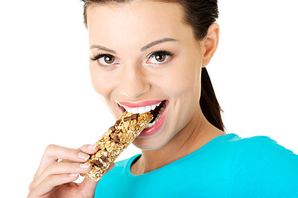 istock Young woman eating Cereal candy bar. 187972439