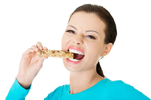 istock Young woman eating Cereal candy bar. 187972450