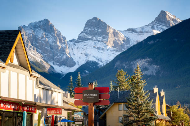 Canmore, AB, Canada - Oct 7 2023 : Canmore Town Sign. The Three Sisters trio of peaks over the blue sky in the background.