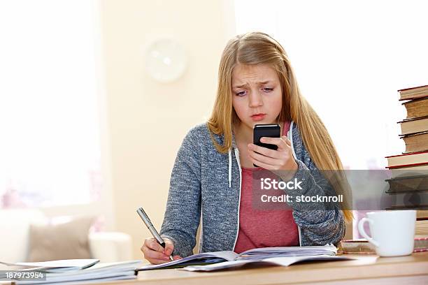 Graves Girl Reading Mensaje De Texto Mientras Que Haciendo Los Deberes Foto de stock y más banco de imágenes de 14-15 años