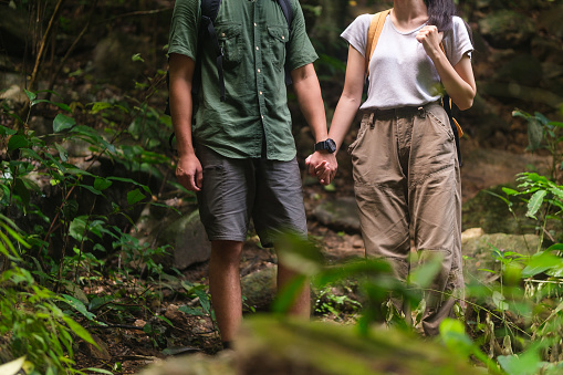 Young couple on a hiking trip walking along the path of the tropical forest. Travel, vacation and active lifestyle concept.