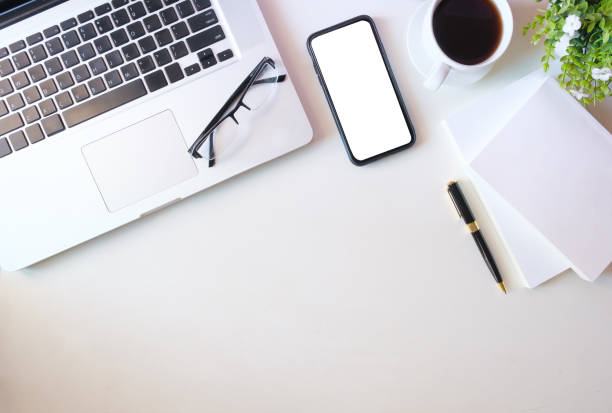 istock Modern workplace with smart phone, laptop computer, coffee cup, eyeglasses and notebook. 1879747177